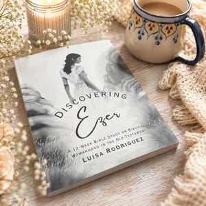 May include: A softcover book titled Discovering Ezer: A 12-Week Bible Study on Biblical Womanhood in the Old Testament by Luisa Rodriguez. The cover features a black and white illustration of a person in a dress standing amidst rocky terrain.