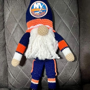 May include: A crocheted gnome wearing a blue and orange New York Islanders hockey jersey with a white beard and black skates.