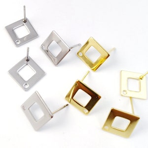 Op de afbeelding: Zes paar oorbel-bevestigingen met een vierkante vorm en een gat in het midden. Drie paar zijn zilverkleurig en drie paar zijn goudkleurig.