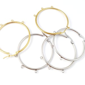 May include: Four hoop earrings, two gold and two silver, with jump rings hanging from the hoops.