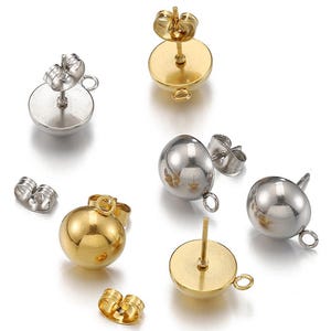 Pode incluir: Uma variedade de brincos de bola dourados e prateados e fechos de brincos. Os brincos têm um pino e um pequeno laço para prender pingentes. Os fechos dos brincos são do estilo borboleta.