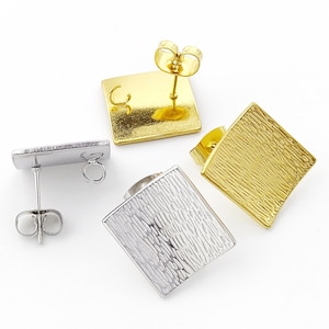 May include: Four square stud earrings in gold and silver. The earrings have a textured surface and a post with a butterfly clutch. The gold earrings have a shiny finish, while the silver earrings have a matte finish. Jewellery.