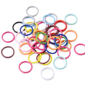 Könnte beinhalten: Ein Haufen bunter Metall-Sprünge in verschiedenen Größen. Die Ringe sind in einem zufälligen Muster angeordnet und alle aus dem gleichen Material.