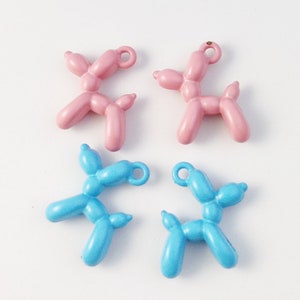 May include: Four balloon animal charms, two pink and two blue, shaped like dogs. The charms have a gold loop for attaching to a necklace or bracelet.