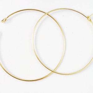 May include: Two gold hoop earrings, each with a simple, circular design. The hoops are made of thin wire and are about 2 inches in diameter.
