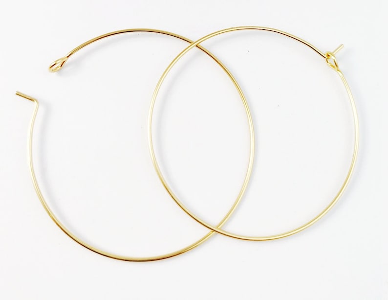 May include: Two gold hoop earrings, each with a simple, circular design. The hoops are made of thin wire and are about 2 inches in diameter.