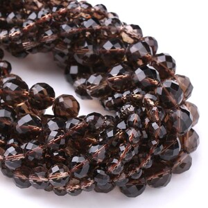 Peut inclure: Un fil de perles de quartz fumé facettées. Les perles sont d'un brun profond avec une coupe à facettes, créant un effet scintillant. Les perles sont enfilées ensemble, formant un collier ou un bracelet.