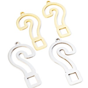 Op de afbeelding: Vier metalen vraagtekenbedels, twee goud en twee zilver, met een gat aan de bovenkant om op te hangen.