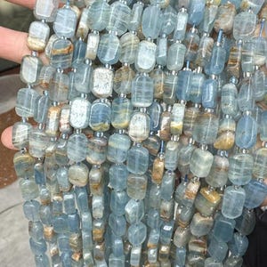 Peut inclure: Brins de perles de pierres précieuses aigue-marine. Les perles sont un mélange de couleurs bleu pâle et bronzé, de forme rectangulaire et de finition polie. Les perles sont enfilées avec un cordon fin et transparent.