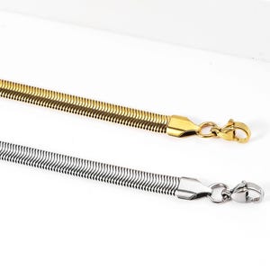 Peut inclure: Deux colliers en chaîne serpent, l'un en or et l'autre en argent. Les deux colliers ont une fermeture à fermoir.