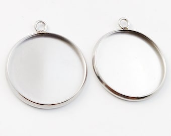 May include: Two silver-toned metal pendant trays with round bezels and a jump ring at the top. The trays are blank and ready for resin or other embellishments.
