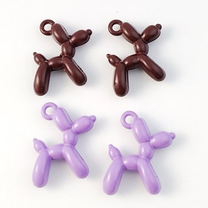 May include: Four balloon animal charms, two brown and two purple, shaped like dogs. The charms have a loop at the top for attaching to a necklace or bracelet.