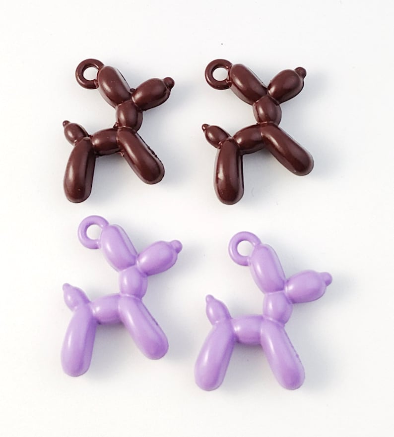 May include: Four balloon animal charms, two brown and two purple, shaped like dogs. The charms have a loop at the top for attaching to a necklace or bracelet.