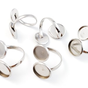 Puede incluir: Seis anillos ajustables de plata con dos engastes redondos de cristal transparente. Los anillos están diseñados para la elaboración artesanal y la creación de joyas.