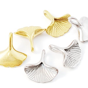 Könnte beinhalten: Sechs Ginkgo-Blatt-Anhänger aus Silber und Gold mit einer Öse zum Anbringen an Schmuck oder andere Bastelarbeiten.