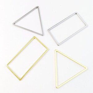 May include: Four metal shapes, two triangles and two rectangles, in gold and silver. The shapes are simple and elegant, perfect for jewellery making or other crafts.