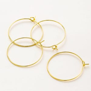 May include: Three gold hoop earrings of different sizes. The hoops are made of thin wire and have a simple, elegant design.