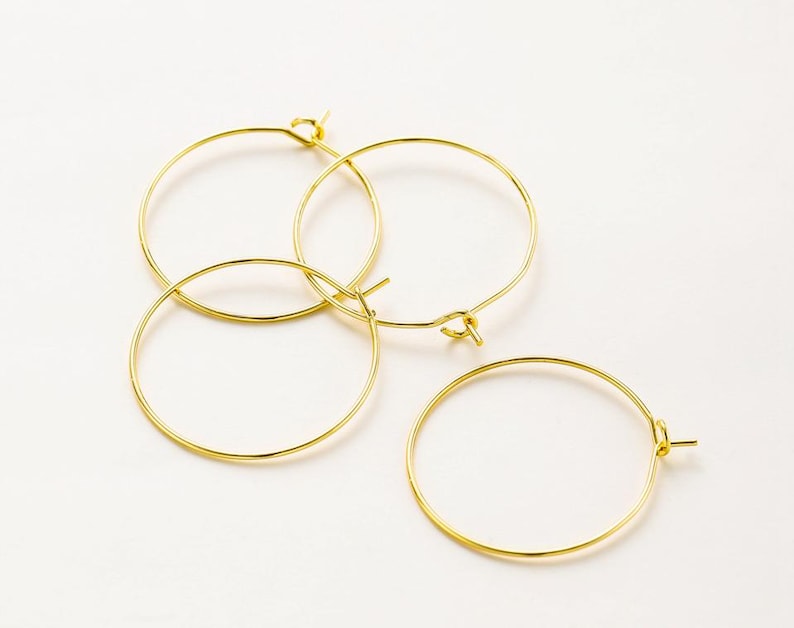 May include: Three gold hoop earrings of different sizes. The hoops are made of thin wire and have a simple, elegant design.