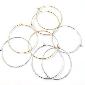 May include: A set of four hoop earrings, two gold and two silver. The hoops are all different sizes and are arranged in a pile.