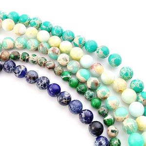 May include: A strand of colorful gemstone beads in shades of blue, green, and white. The beads are round and have a marbled or speckled pattern.