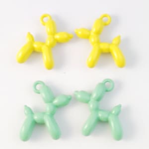 May include: Four balloon animal charms, two yellow and two light green, shaped like dogs. Each charm has a small loop for attaching to a necklace or bracelet.