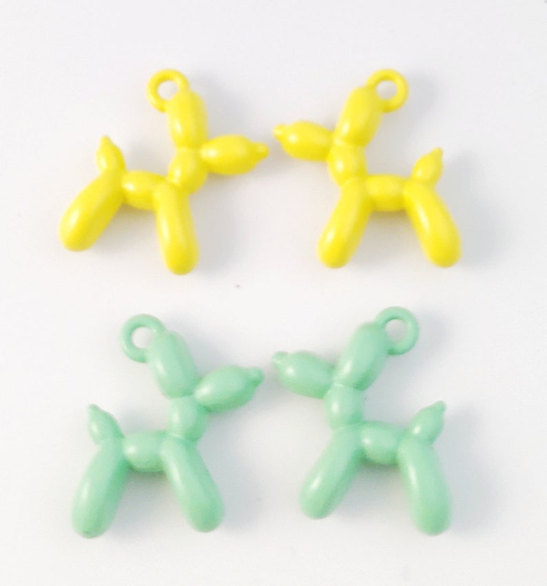 May include: Four balloon animal charms, two yellow and two light green, shaped like dogs. Each charm has a small loop for attaching to a necklace or bracelet.