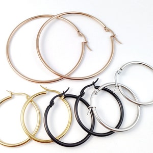 Puede incluir: Un conjunto de cuatro pendientes de aro en diferentes tamaños y colores. Los pendientes están hechos de acero inoxidable y están disponibles en oro, plata y negro.