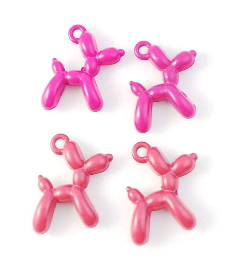 May include: Four balloon animal charms in pink and red. The charms are shaped like dogs and have a loop at the top for attaching to a necklace or bracelet.