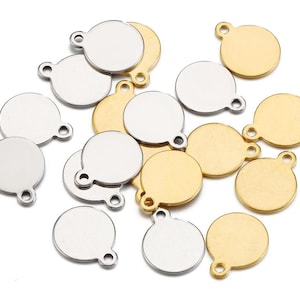 Könnte beinhalten: Eine Sammlung runder Metallanhänger mit einem Loch oben. Die Anhänger sind in zwei Farben: Gold und Silber. Die Anhänger sind alle gleich groß und gleich geformt.