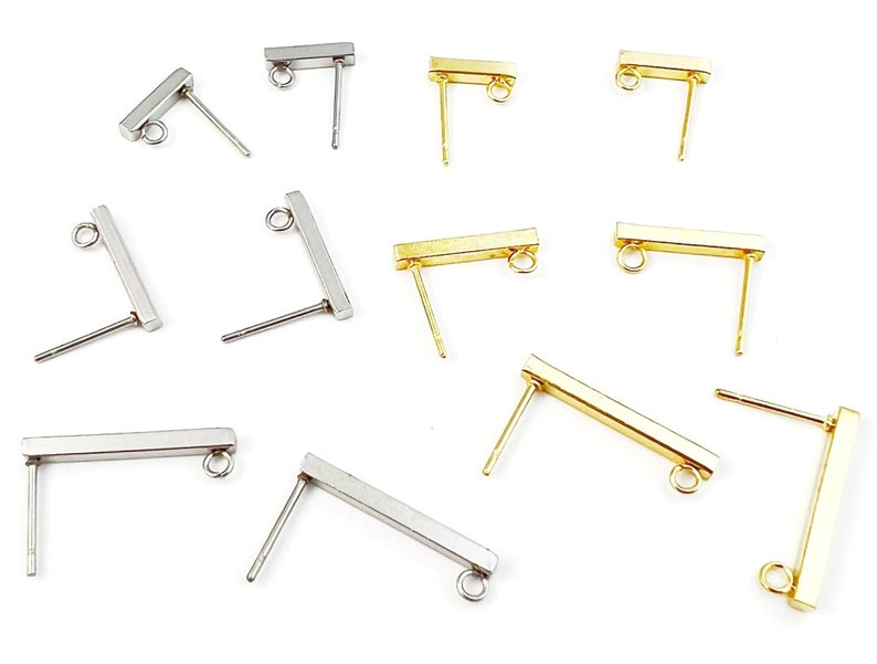 Pu&ograve; includere: Assortimento di componenti per orecchini rettangolari in oro e argento con un anello nella parte superiore. I componenti hanno un perno nella parte inferiore per essere fissati a un orecchino.