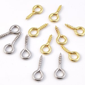 May include: A collection of screw-in eyelet hooks in gold and silver finishes. The hooks are ideal for attaching to fabric, leather, or other materials.