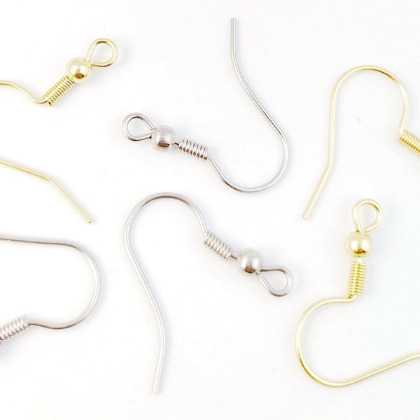 Puede incluir: Primer plano de varios ganchos para pendientes en tonos dorados y plateados. Los ganchos tienen un diseño curvo con un lazo en la parte superior y un detalle de resorte en espiral. Los ganchos están diseñados para la fabricación de joyas y manualidades.