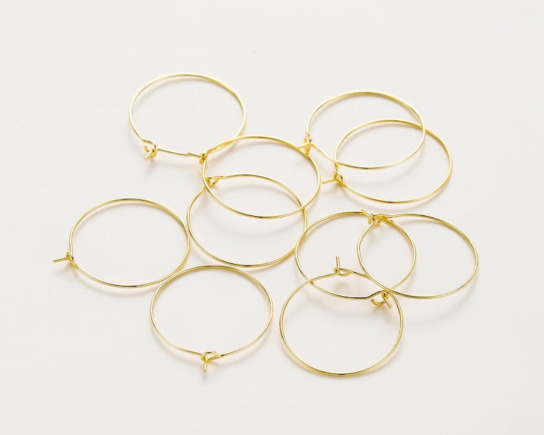 May include: A set of eight gold-toned hoop earrings. The hoops are of varying sizes and are arranged in a cluster.