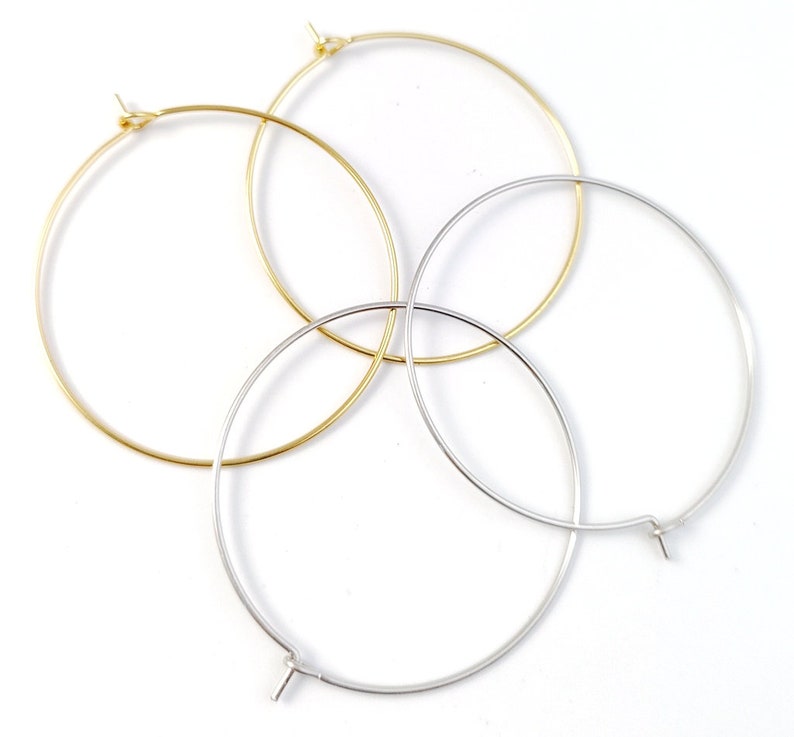 May include: Three hoop earrings, one gold and two silver, are arranged on a white background. The hoops are all the same size and have a simple, elegant design.