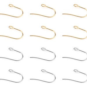 Puede incluir: Una colección de doce ganchos para pendientes de metal dispuestos en una cuadrícula. Las dos filas superiores presentan seis ganchos dorados, mientras que las dos filas inferiores consisten en seis ganchos plateados con un pequeño bucle.