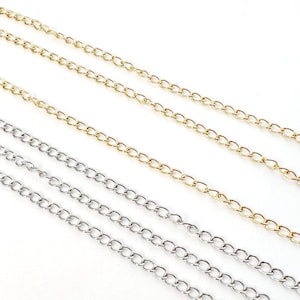 Könnte beinhalten: Drei Kettenstränge, zwei goldfarben und einer silberfarben, liegen auf einer weißen Oberfläche. Die Ketten sind alle im gleichen Stil, mit einem einfachen, ovalen Glied.