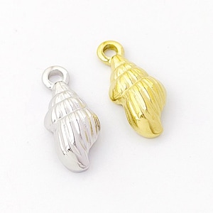 May include: Two small seashell charms, one silver and one gold. The charms are detailed with ridges and have a loop at the top for attaching to jewellery.