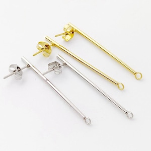 Może przedstawiać: Dwie pary zapięć do kolczyków, jedna para jest złota, a druga srebrna. Każde zapięcie ma pętelkę na końcu i sztyft z zapięciem motylkowym.