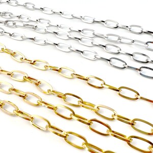 Könnte beinhalten: Nahaufnahme von zwei Reihen ovaler Kettenglieder in Gold und Silber. Die Ketten liegen parallel auf einem weißen Hintergrund.