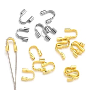 Może przedstawiać: Zbiór złotych i srebrnych koralików do zaciskania do tworzenia biżuterii. Koraliki mają kształt litery U i służą do zabezpieczania drutu lub sznurka.