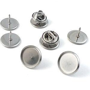 Może przedstawiać: Zestaw sześciu srebrnych metalowych pleców do przypinek do tworzenia spersonalizowanych przypinek. Plecy do przypinek mają okrągłą podstawę z szpilką i zatrzaskiem na górze.