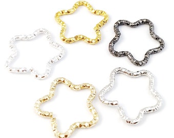 Könnte beinhalten: Fünf sternförmige Sprungringe in verschiedenen Metalloberflächen: Gold, Silber, Schwarz und zwei Goldtönen. Die Ringe sind strukturiert und haben einen leicht gewellten Rand.
