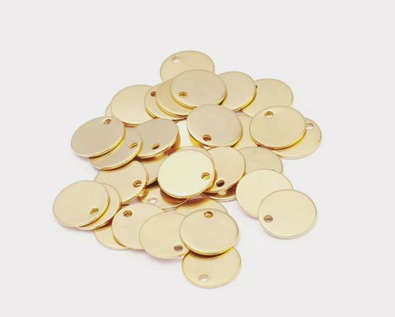 Pu&ograve; includere: Un mucchio di dischi rotondi in metallo dorato con un piccolo foro al centro. I dischi hanno un diametro di circa 2,5 cm.