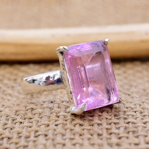 May include: A silver ring with a large, rectangular, light pink gemstone.