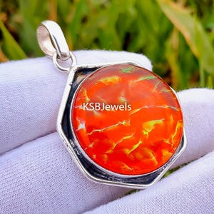 May include: A silver pendant with a red, orange, and yellow opal gemstone. The pendant is in the shape of a hexagon and has a bail for attaching to a chain. The opal has a unique, cracked pattern.