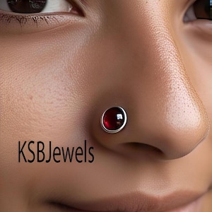 May include: A close-up of a person's nose with a small, silver nose ring featuring a red gemstone. The text "KSBJewels" is visible in the bottom left corner of the image.