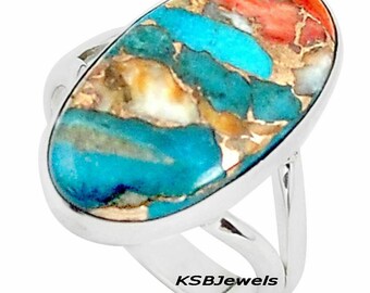May include: A silver ring with a large oval turquoise stone. The stone has a unique pattern of blue, green, and brown colors.
