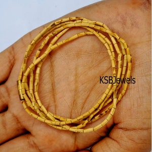 Pu&ograve; includere: Una collana multifilo realizzata con perline di legno naturale. Le perline sono piccole e rettangolari, e la collana &egrave; chiusa con un fermaglio dorato. La collana &egrave; mostrata su una mano, e il marchio "KSBJewels" &egrave; visibile nell'immagine.