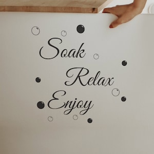May include: White bathtub with a black and white vinyl decal that reads "Soak Relax Enjoy" with small circles around the text.