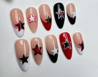 May include: Set of ten false nails with a white tip and a black or red base. Each nail has a star design with black and red accents.